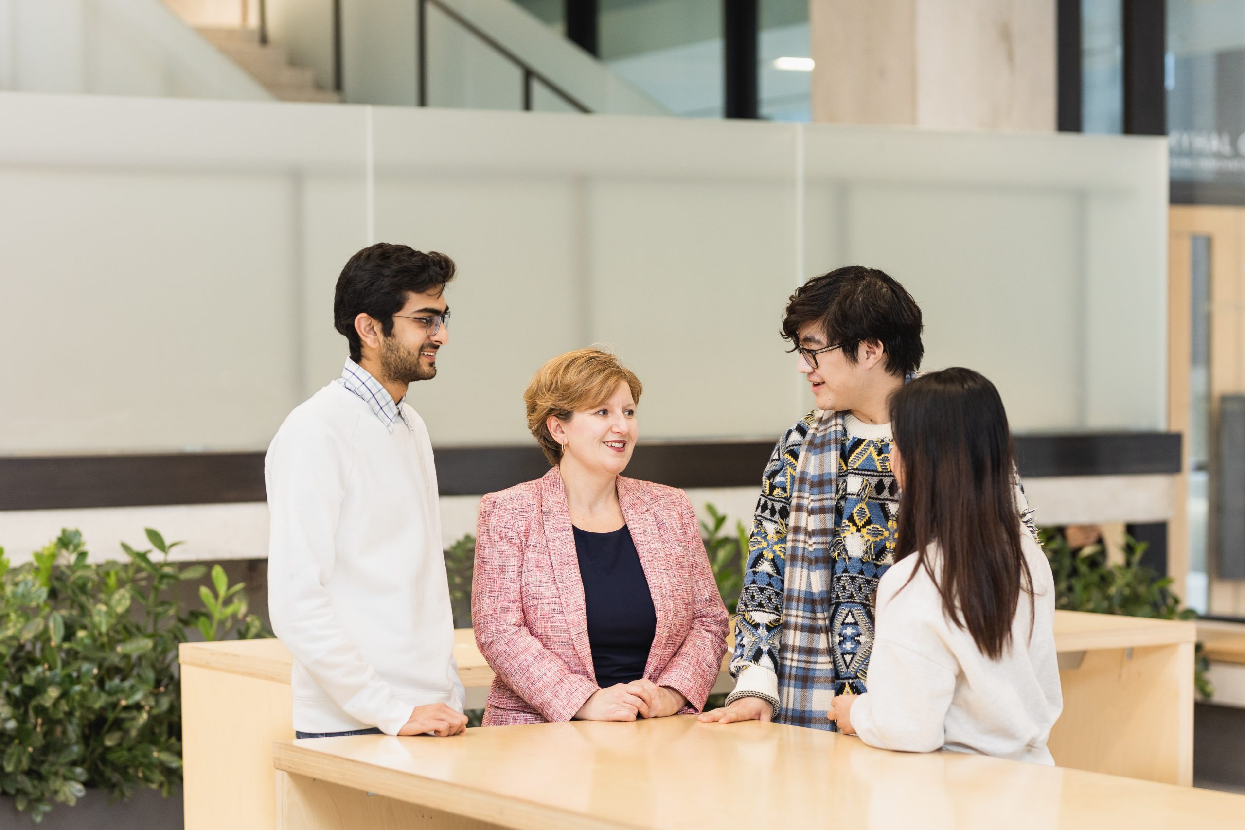 Helen Bright standing by a table with three undergraduate engineering students.