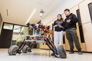 Robotics for space exploartion members using a controller while standing beside the rover. 