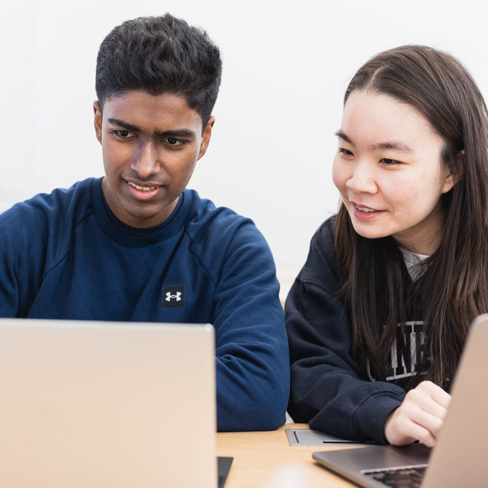 Two students looking at their laptops.